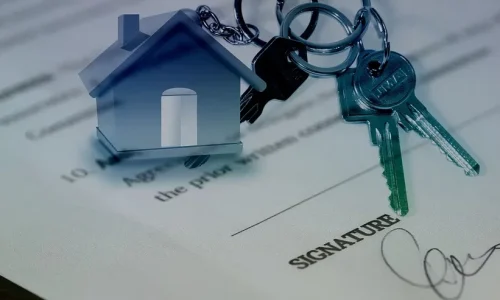 Nahaufnahme eines Dokuments mit einer Unterschrift darunter und einem Schlüsselbund, der an einem hausförmigen Schlüsselanhänger befestigt ist. Der Fokus auf die Schlüssel deutet auf Eigentums- oder Immobilienthemen hin – ideal für diejenigen, die mit Vires Immobilienmakler in Wien eine Wohnung verkaufen möchten.